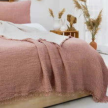 Bedroom with pink bedding and decorative hats on the wall