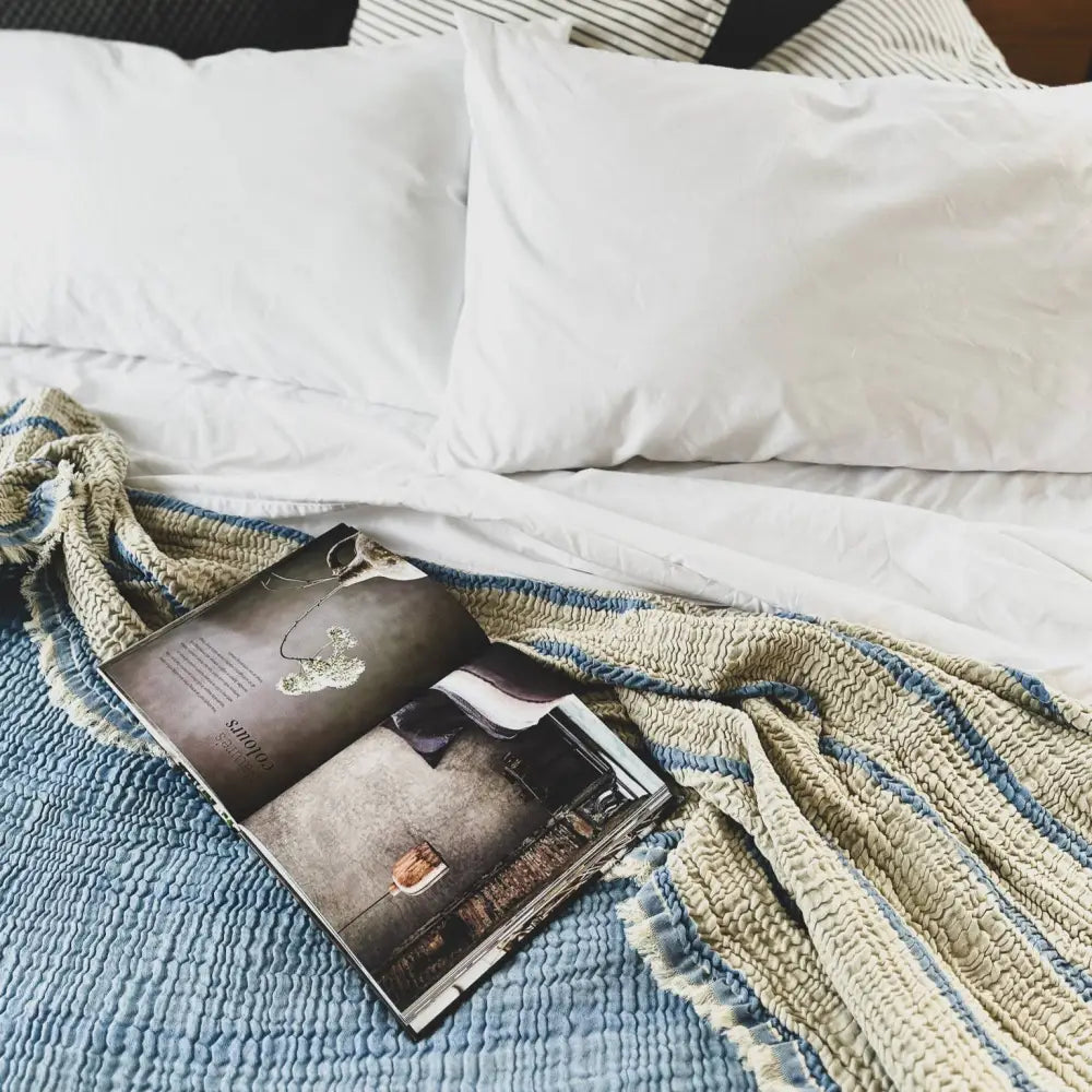 Blue muslin bed blanket with stripes on one side.