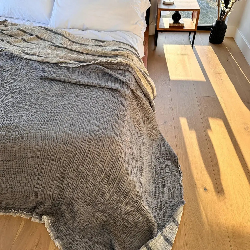 Gray muslin bed blanket that reverses to stripes of gray and ecru.