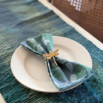 Gold dragonfly napkin ring holding a folded blue green floral napkin from fair trade bali workshop green floral set