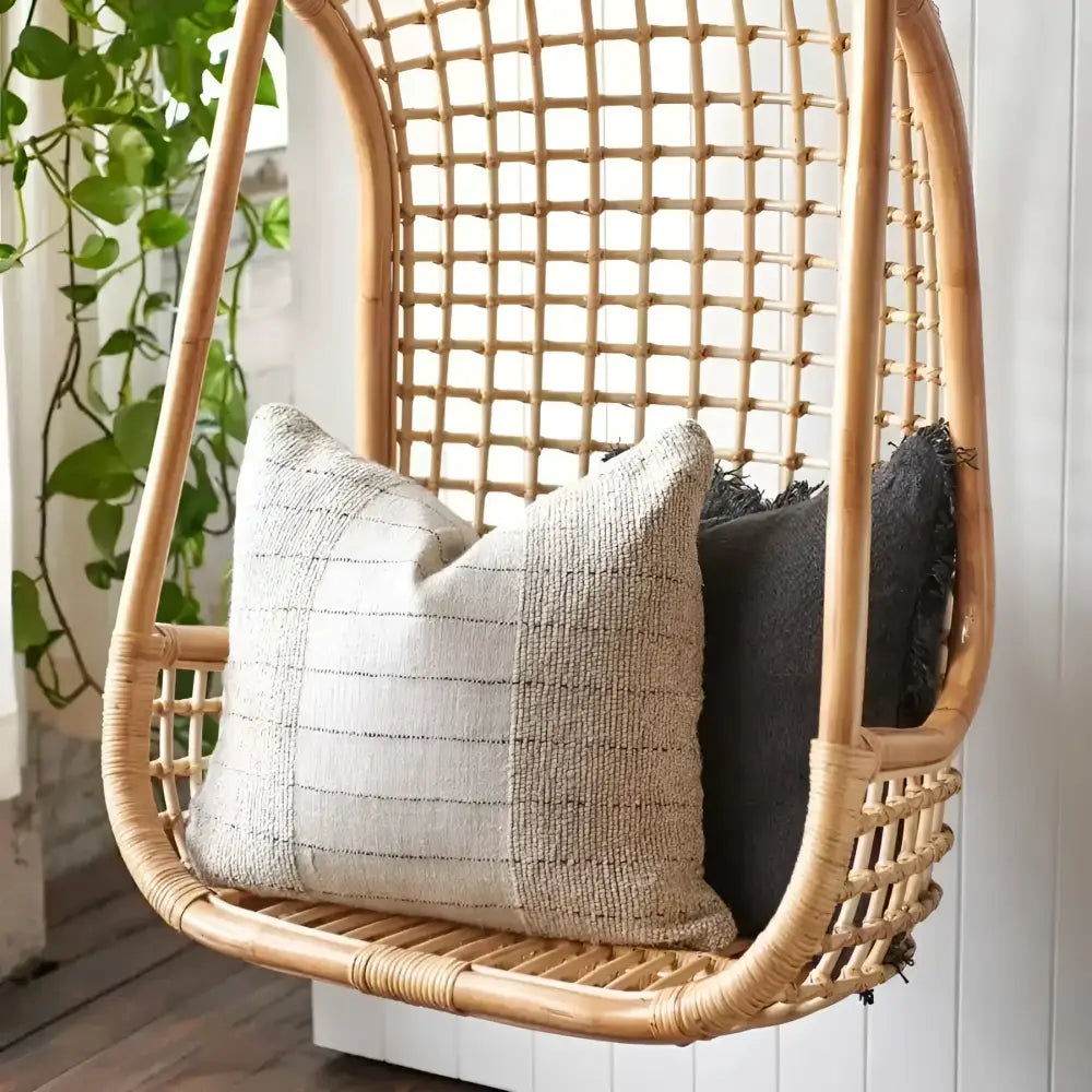 Textured pillow in natural color with black stripes on a wicker swing.