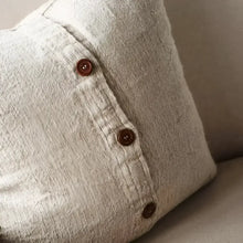 Textured pillow in natural color with black stripes and close up of buttons.