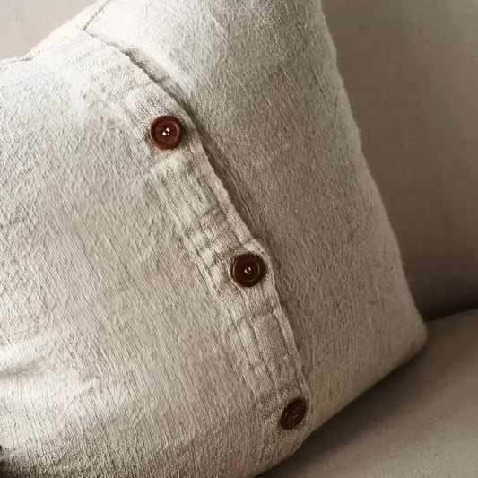 Textured pillow in natural color with black stripes and close up of buttons.