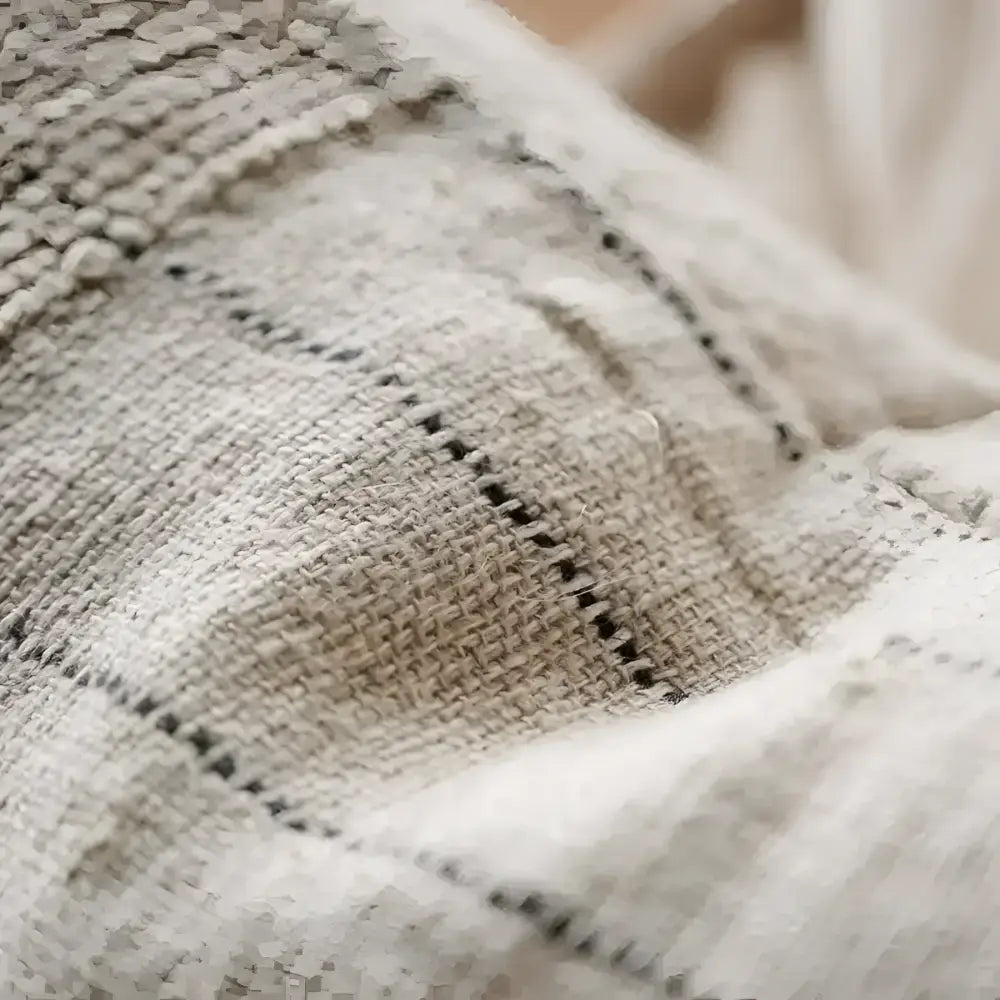 Close up of textured pillow in natural color with black stripes.