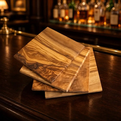 Stacked olive wood four square coasters handcrafted with natural swirling grain patterns in warm brown and golden hues