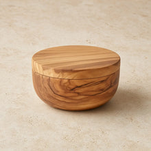 A round handcrafted olive wood dual compartment spice and herb cellar with smooth finish and swiveling magnetic lid