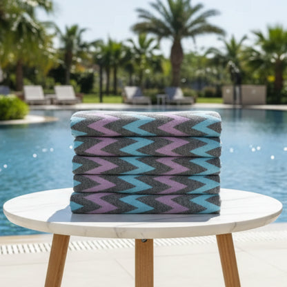 Stack of folded organic bath towels with bold teal lavender and charcoal zigzag pattern perfect for beach use