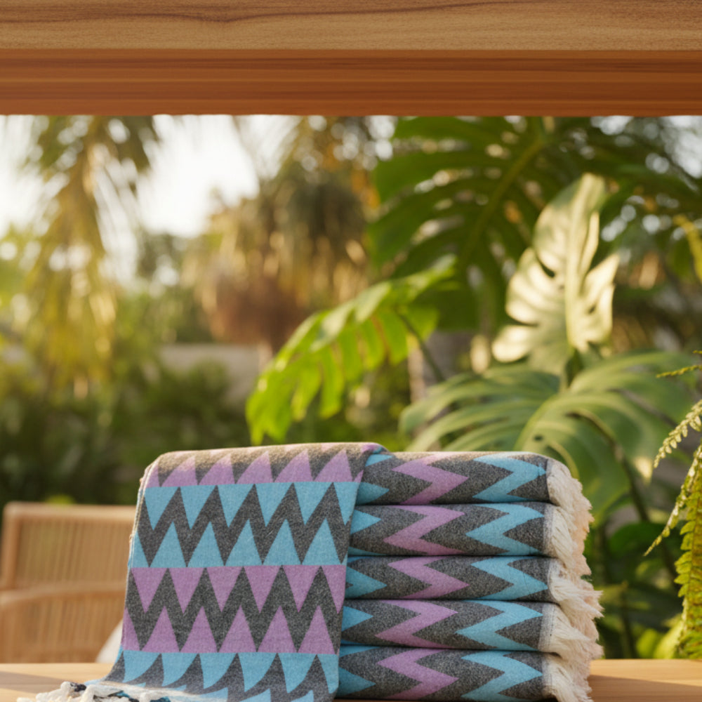 Stack of folded organic bath towels with bold purple teal and black zigzag pattern perfect for beach use