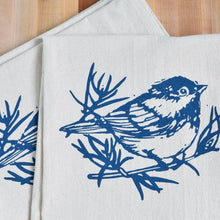A white cloth napkin, hand-printed with an original Chickadee design in navy blue. 
