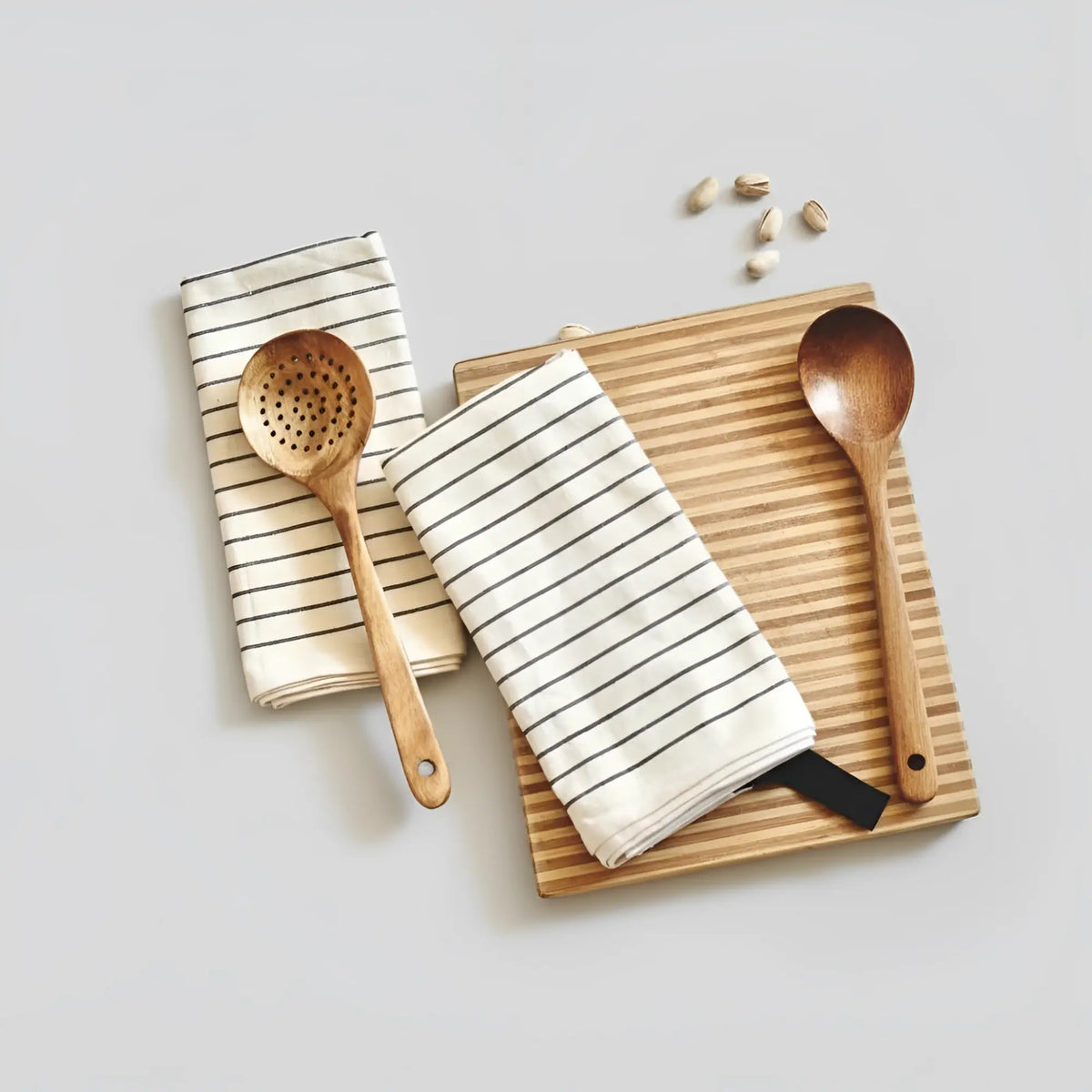 Slotted wooden spoon with black handle on organic cotton tea towel
