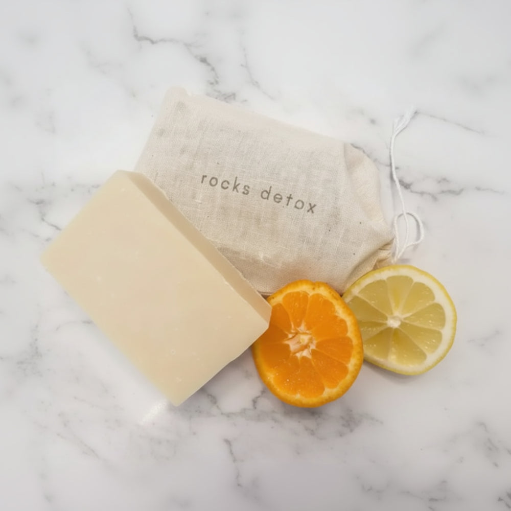 Organic shea butter soap with cactus pear beside rocks detox bag and citrus slices