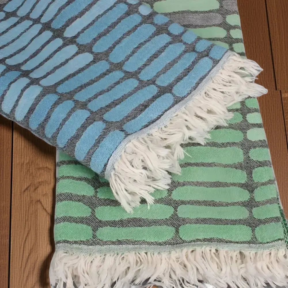 Two fringed Turkish towels in blue and green with oval pattern, quick drying and sand resistant