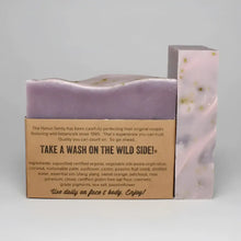 Purple handmade passionflower bar soap with speckled green flecks wrapped in kraft paper featuring ylang ylang and passion fruit seed