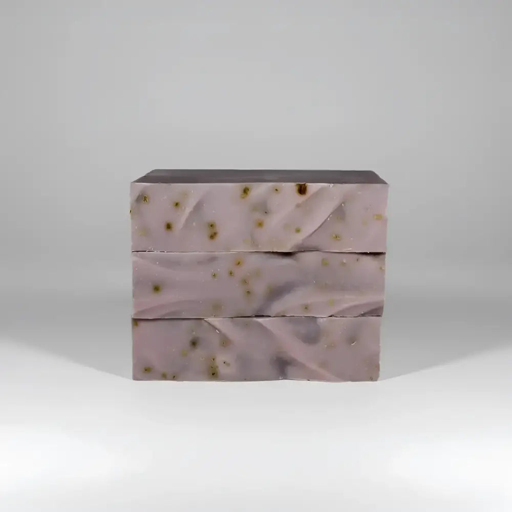Three stacked bars of lavender passionflower soap with marbled texture and golden botanicals with ylang ylang and oats