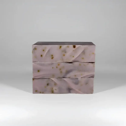 Three stacked bars of lavender passionflower soap with marbled texture and golden botanicals with ylang ylang and oats