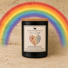 Black cylindrical handmade soy wax candle with wooden lid and rainbow paw print label from black dog candle shoppe