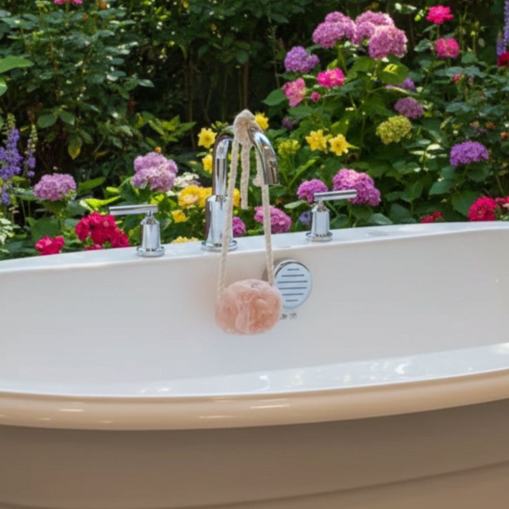 Cream freestanding tub with chrome faucet beside pink Himalayan bath salt rock