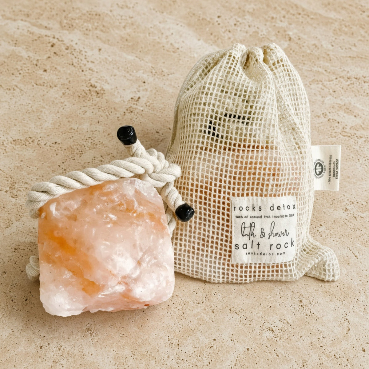 Pink himalayan hanging bath and shower salt rock with rough crystalline surface and black-tipped organic cotton rope ties
