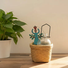 Turquoise garden angel with leafy arms beside propagation vase in basket