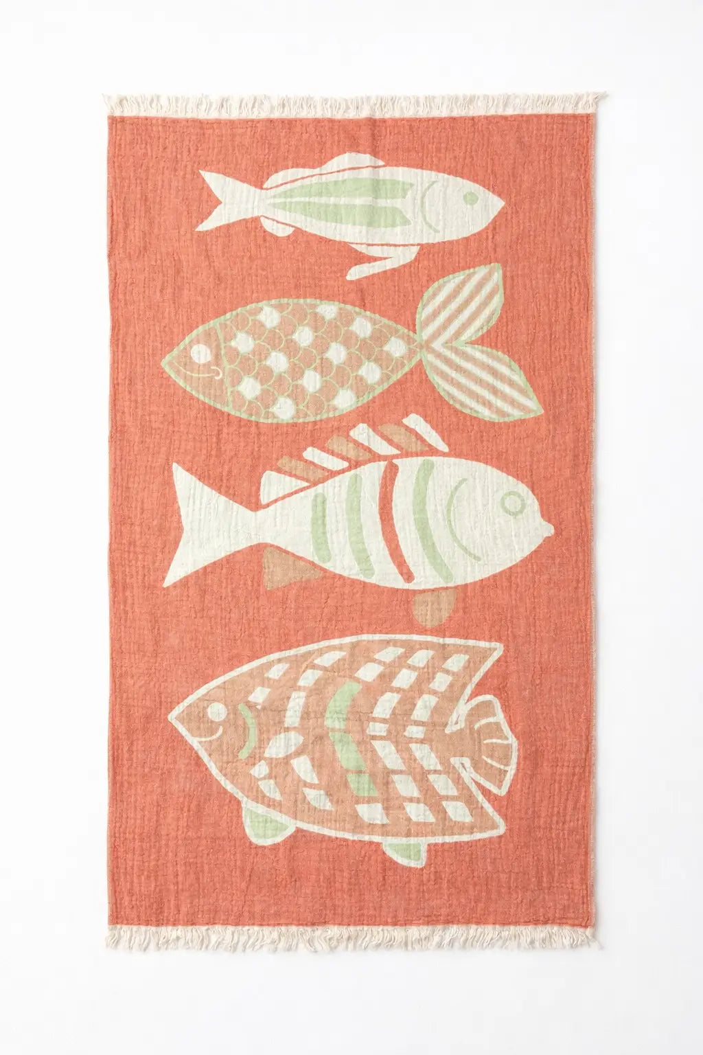 Coral-colored turkish cotton beach towel with four white and light green fish patterns and fringed edges perfect as a beach blanket