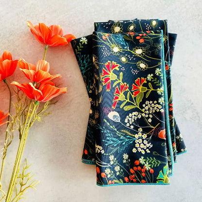 Folded dark pretty peacock cloth napkins with colorful floral pattern and teal edging