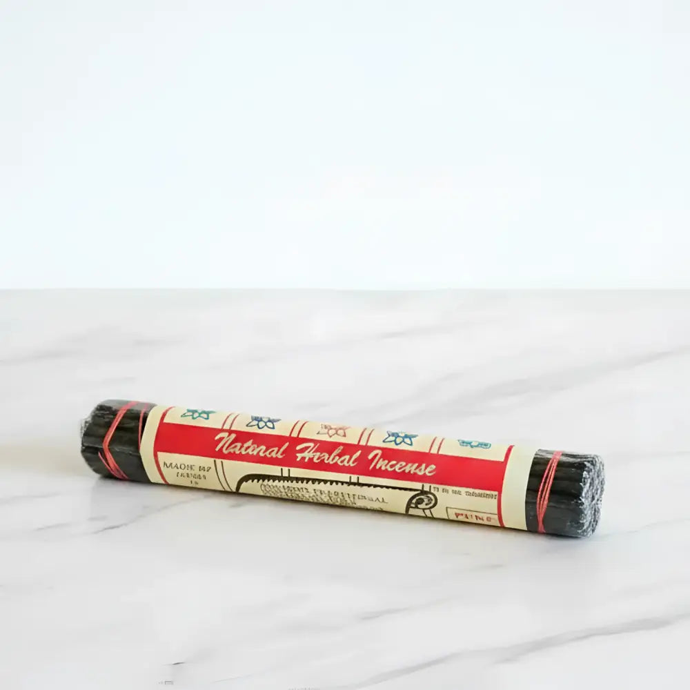A roll of black pure herbal incense sticks wrapped in red cream paper with blue patterns handmade by newari nuns