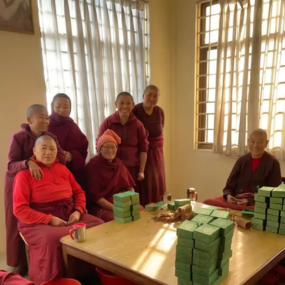 Stacks of green rectangular boxes of pure natural incense made by tibetan nuns from khachoe ghakyil ling nunnery on table