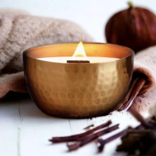 Lit soy candle with wooden wick in a hammered solid brass bowl with crushed thyme herb