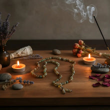 A rainbow agate mala necklace with translucent green and amber-colored beads and a beaded tassel on wood