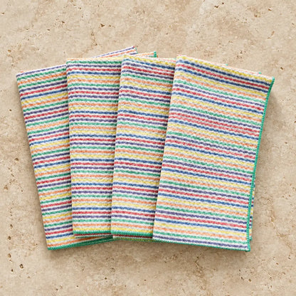 Set of four rainbow seersucker cloth napkins with vibrant multicolored horizontal stripes in a textured weave