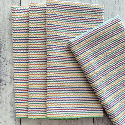 Set of four colorful rainbow seersucker cloth napkins with red green blue and yellow stripes in waffle weave texture