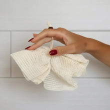 Cream-colored ramie shower pouf made from textured ramie plant fibers with loop handle for natural exfoliation experience