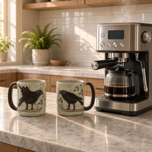 Two black bird designed ceramic mugs on a light speckled surface from mara ceramica stoneware xl sturdy collection