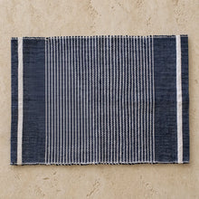 Navy blue and white striped woven placemat made from recycled cotton scraps with frayed edges for eco-friendly dining