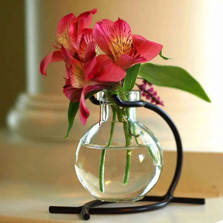 Recycled glass mini vase with black metal stand holding pink flowers