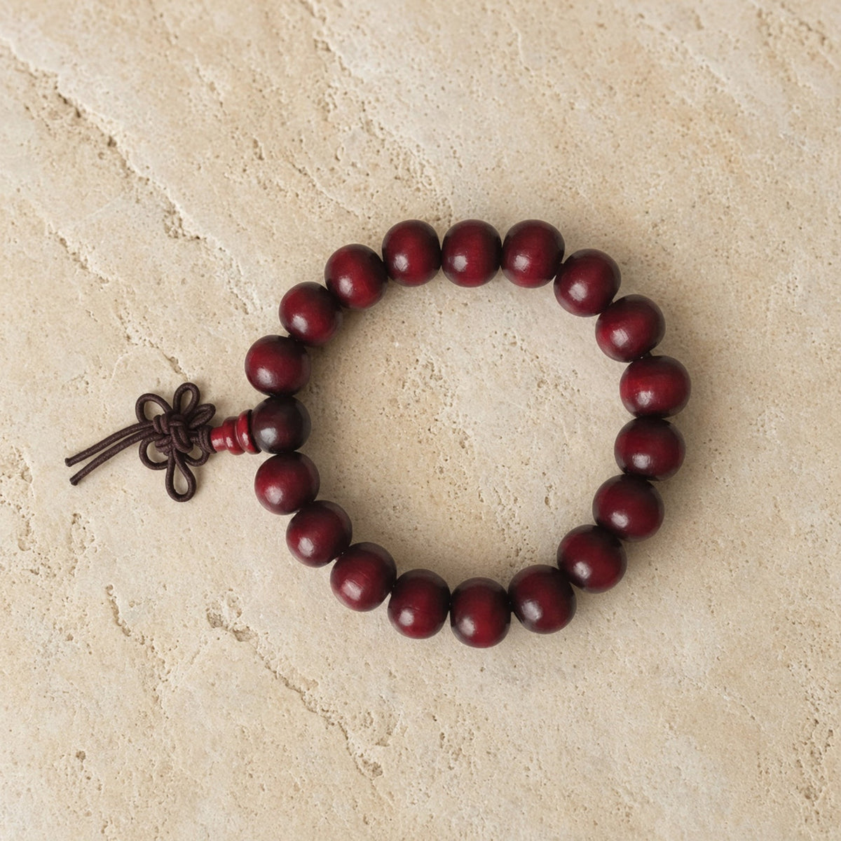 A dark red rosewood bracelet with plain 8mm beads and knotted cord perfect for essential oils use