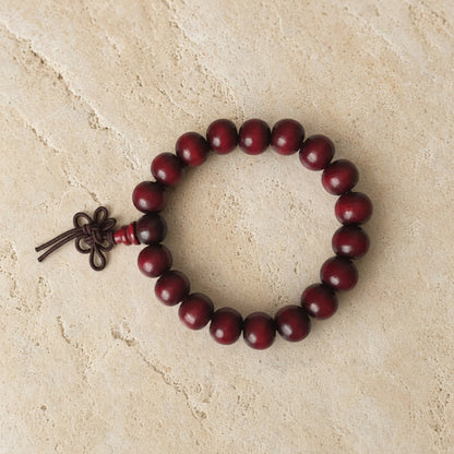 A dark red rosewood bracelet with plain 8mm beads and knotted cord perfect for essential oils use