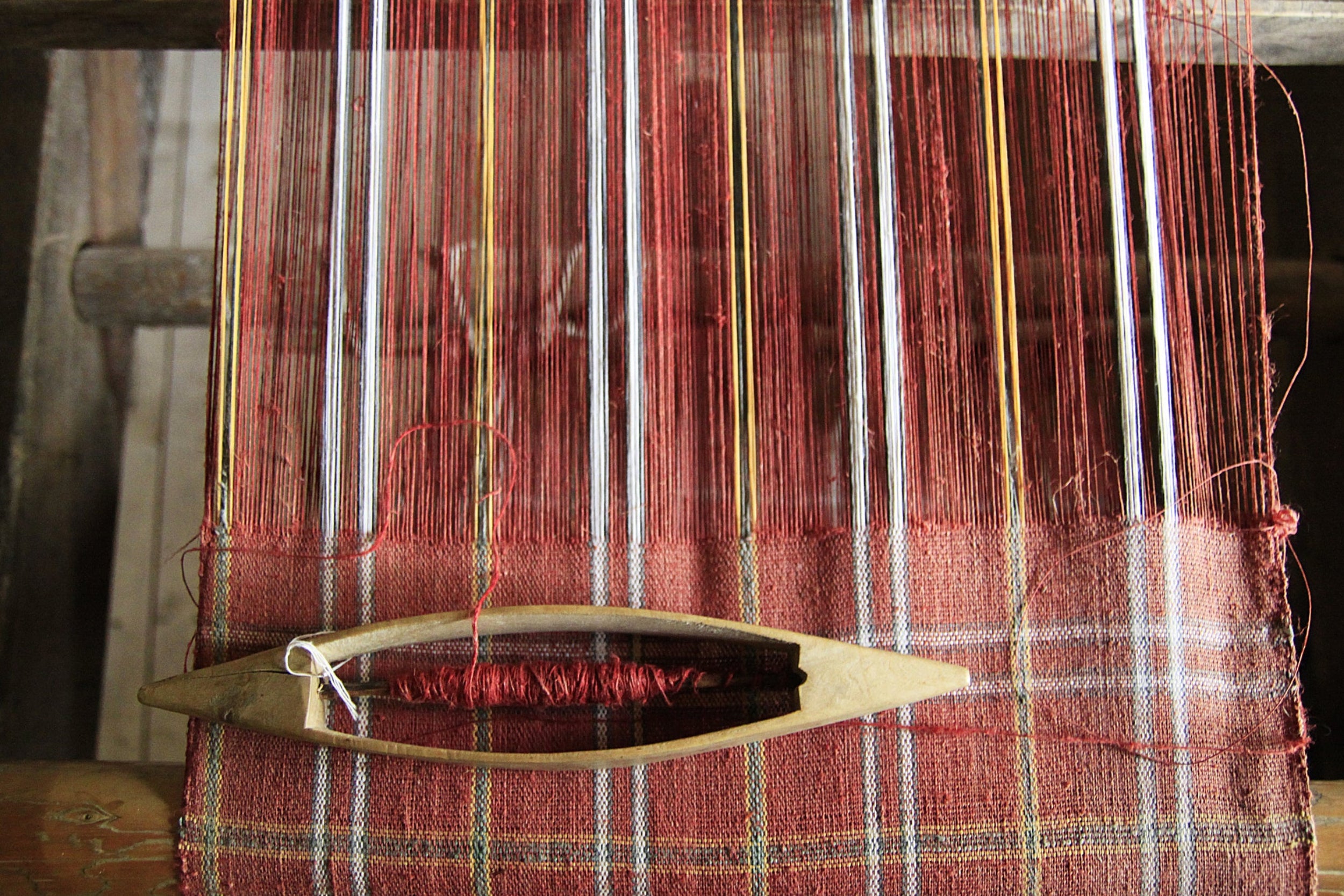Weaving loom with red and gold threads on a wooden frame
