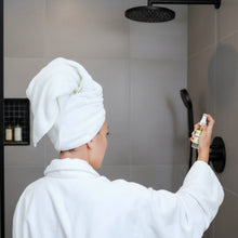 Hand holding sleek Zatri Replenish Ylang-Ylang shower mist bottle