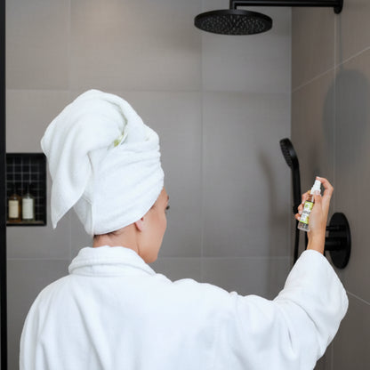 Hand holding sleek Zatri Replenish Ylang-Ylang shower mist bottle