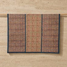 A reversible compass paisley print compass tablecloth with terracotta and green motifs on textured fabric and navy border
