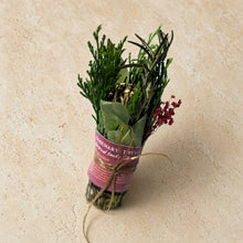 A bundle of rosemary thyme and bay leaf smudge tied with a gold ribbon for purifying energy and smoke rituals