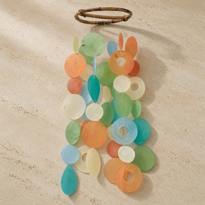 A round capiz chime with colorful orange blue and green sea glass pieces hanging from a woven bamboo ring fish village style