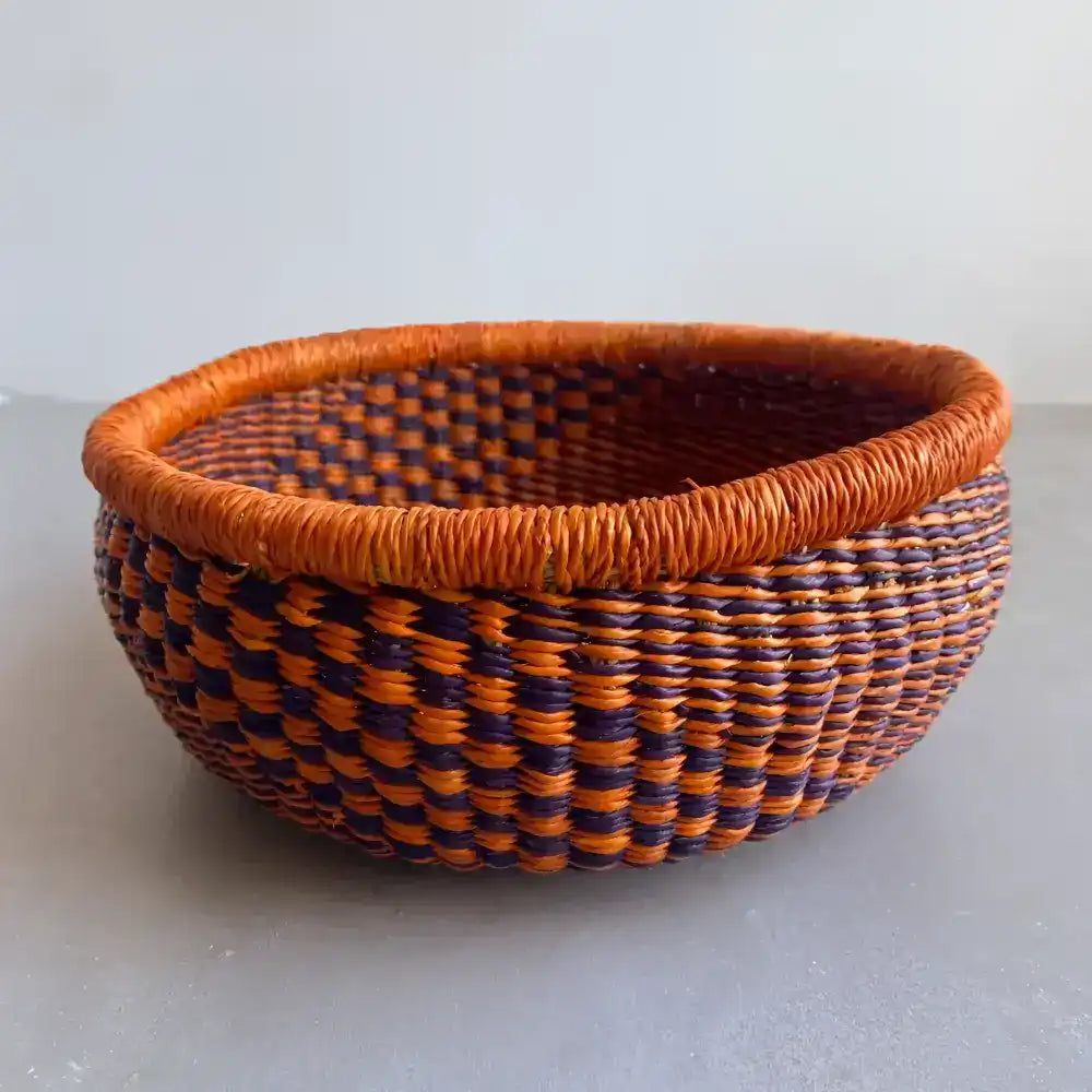 Round basket with bright orange coloring on a gray surface.