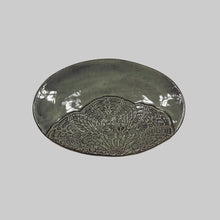 Decorative dish with lace imprints on a white surface