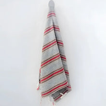 Turkish towel that has a flat weave and has brown, rusty red, and very thin turquoise stripes.