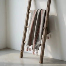 A soft gray woven rust and brown striped turkish towel with pink white stripes and tassels made from handcrafted turkish cotton