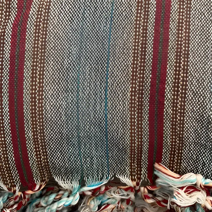 Turkish towel that has a flat weave and has brown, rusty red, and very thin turquoise stripes.
