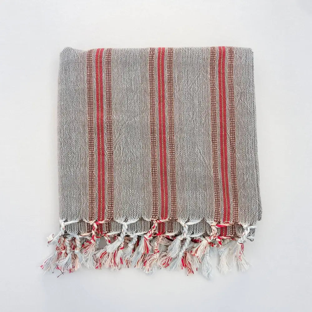 Turkish towel that has a flat weave and has brown, rusty red, and very thin turquoise stripes.