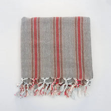 Turkish towel that has a flat weave and has brown, rusty red, and very thin turquoise stripes.